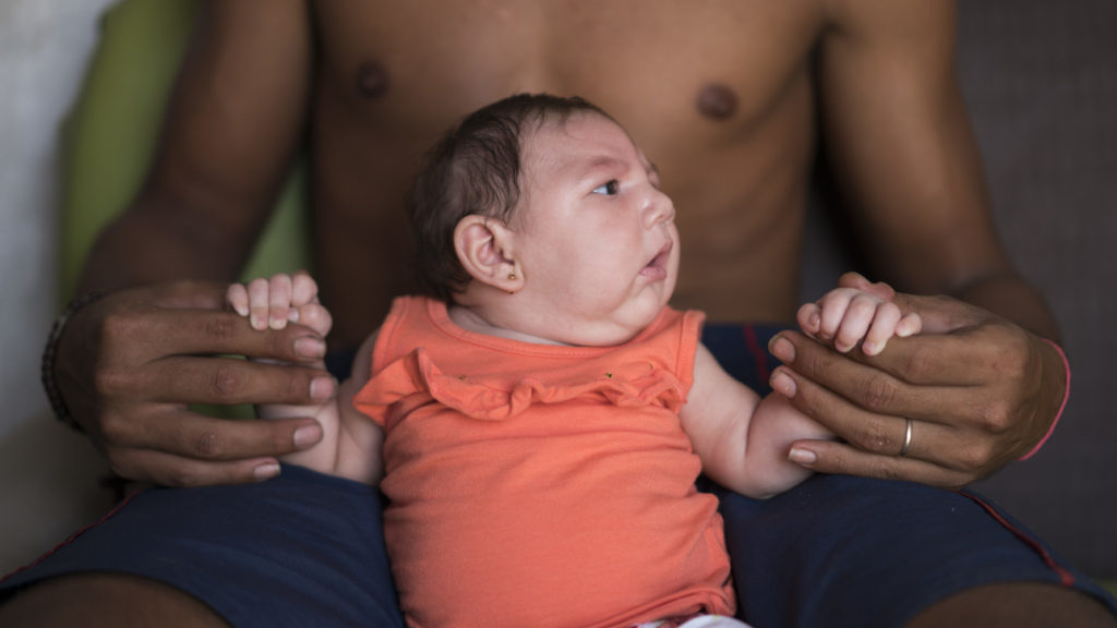 23 Dec 2015, Brazil --- In this Dec. 23, 2015 photo, Dejailson Arruda holds his daughter Luiza at their house in Santa Cruz do Capibaribe, Pernambuco state, Brazil. Luiza was born in October with a rare condition, known as microcephaly. Luiza's mother Angelica Pereira was infected with the Zika virus after a mosquito bite. Brazilian health authorities are convinced that Luiza's condition is related to the Zika virus that infected her mother during pregnancy. (AP Photo/Felipe Dana) --- Image by © Felipe Dana/AP/Corbis